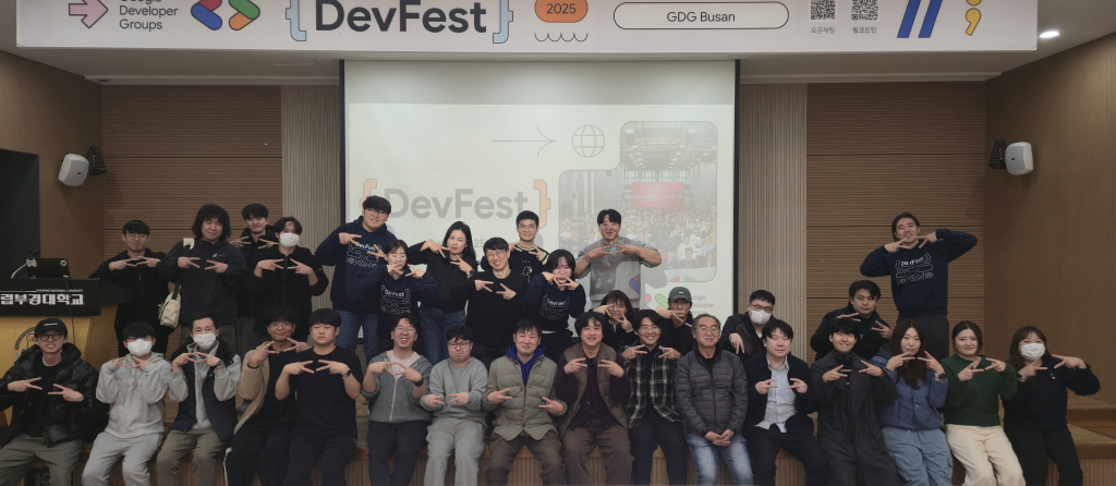 Group photo of participants at DevFest 2025 in Busan, organized by Google Developer Groups (GDG), posing together on stage in front of the event banner.
